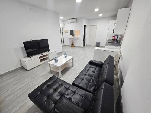 Una sala de estar con un sofá de cuero y una mesa. en Apartamento mi currilla, en Sanlúcar de Barrameda