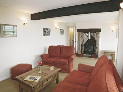 ein Wohnzimmer mit einer Couch, einem Sessel und einem Tisch in der Unterkunft Vale View Cottage in Cinderford