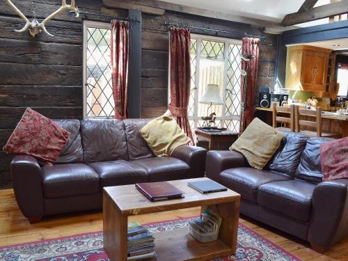 a living room with a leather couch and a table at Brook Barn in Ellingham