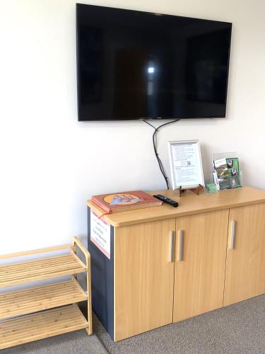 a flat screen tv on top of a wooden cabinet at Birch Court - Harakeke in Whanganui