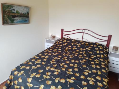 a bed with a blue bedspread with yellow flowers on it at Es aca in Jaureguiberry