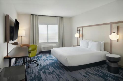 a hotel room with a large white bed and a desk at Fairfield by Marriott Inn & Suites Columbus in Columbus