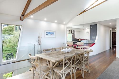 a kitchen and dining room with a wooden table and chairs at Pure Indulgence in Merimbula