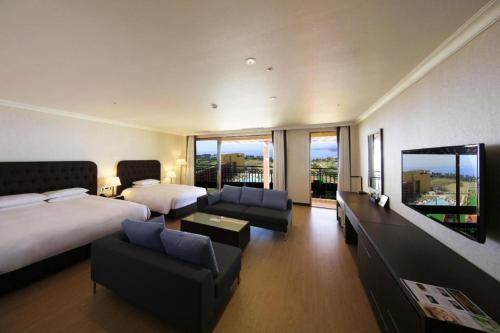 ソギポにあるJeju Booyoung Hotelのベッド2台とリビングルームがあるホテルの部屋