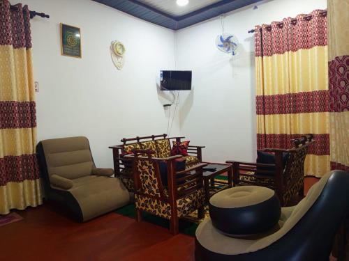 a room with chairs and a table and a tv at Wilpattu Gagana guest in Nochchiyagama