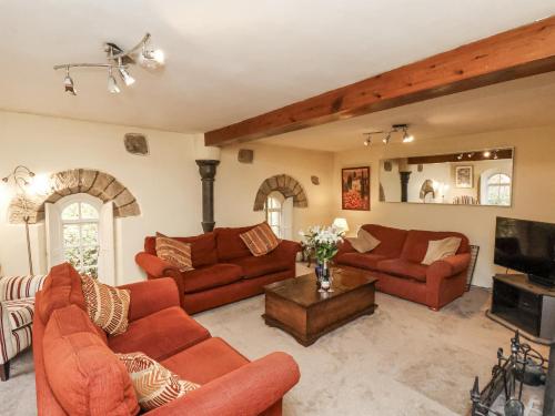 a living room with red couches and a tv at 1 The Old Methodist Chapel in Rosedale Abbey