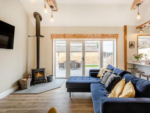 Una sala de estar con un sofá azul y una chimenea. en Dip Tub Den - Uk35989, en Wansford