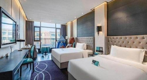 een hotelkamer met twee bedden en een bureau bij Xana Hotelle Luzhou High-Speed Railway Station Trading Market Passenger Terminal in Luzhou