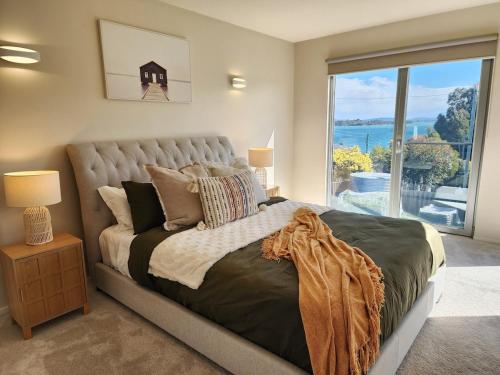 a bedroom with a large bed with a large window at 138 On The Bay - Sunset Bliss on the Waters Edge in Murdunna