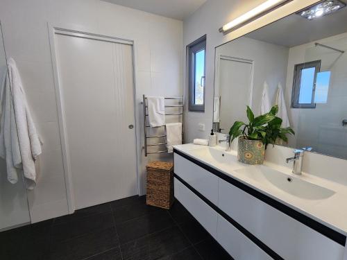 a white bathroom with a sink and a mirror at 138 On The Bay - Sunset Bliss on the Waters Edge in Murdunna
