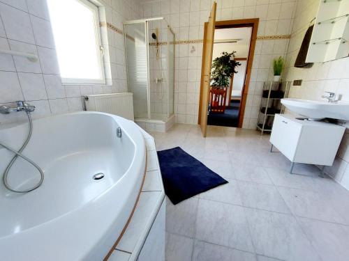 a white bathroom with a tub and a sink at Guesthouse Graz Central for 9 People in Graz