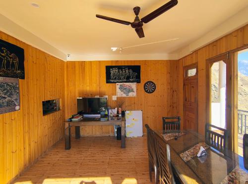 a living room with wooden walls and a ceiling fan at The VOID - Tirthan Valley in Gushaini