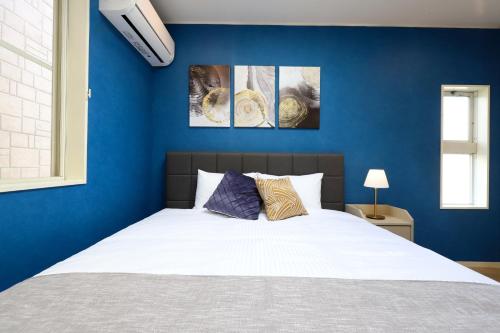 a bedroom with blue walls and a white bed at Real Stay Tokyo Bay ,Funabashi in Funabashi