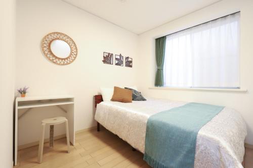 a bedroom with a bed and a table and a mirror at Real Stay Tokyo Bay ,Funabashi in Funabashi
