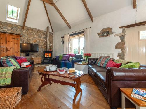 Una sala de estar con sofás de cuero y una mesa. en Ty Dewi - Qc1507, en Llanhowell