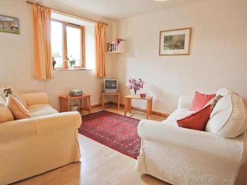 a living room with two white chairs and a red rug at Bridle Cottage in Hoarwithy