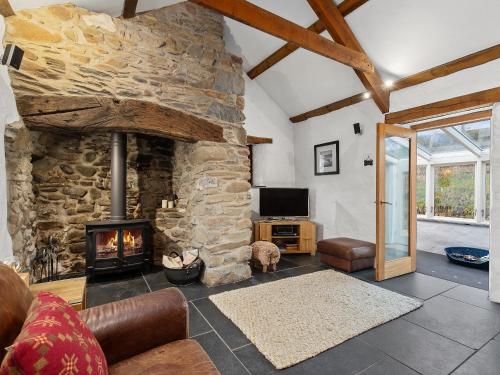 ein Wohnzimmer mit einem Steinkamin und einem TV in der Unterkunft Temple Cottage in Abercastle