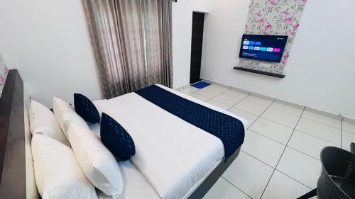 a bedroom with a bed with pillows and a tv at The lawrences aqua stay in Cochin