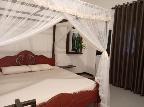 a bedroom with a canopy bed with white curtains at The Onisula Guest House in Ahangama