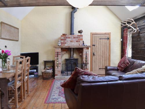 a living room with a couch and a fireplace at Brook Barn in Ellingham
