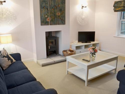 un salon avec un canapé, une table et une cheminée dans l'établissement Tower Cottage - Mvw, à Belsay