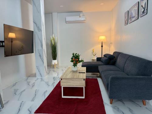 a living room with a blue couch and a red rug at Together Stay Home in Mae Sai