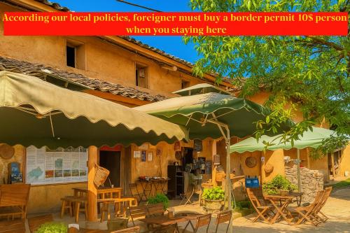 a restaurant with tables and umbrellas in front of a building at Long Cổ Trấn Homestay in Dồng Văn