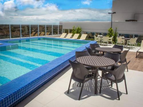 a swimming pool with a table and chairs next to a building at Studio Sofisticado 2106 - Próx Aeroporto GRU in Guarulhos