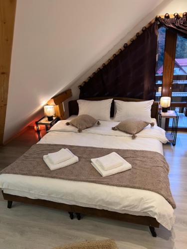 a bedroom with a large bed with two towels on it at Kalinderu Slope View in Buşteni