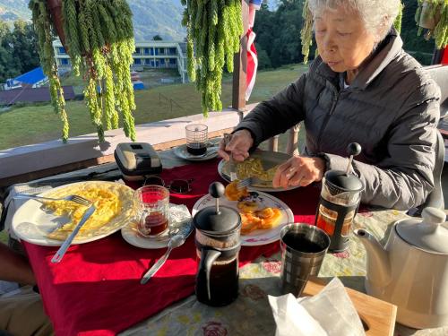 une femme âgée assise à une table avec des assiettes de nourriture dans l'établissement The Hotel Orchid & Restaurant, à Kāskī