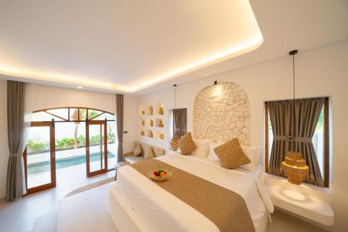a white bedroom with a large bed and a pool at Dianatara Villa by Dhananjaya Hospitality in Sukawati