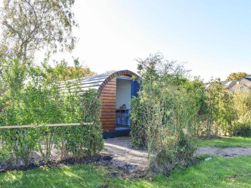 une petite maison en bois avec une porte bleue dans une cour dans l'établissement Privet Pod - Uk41394, à Westhead