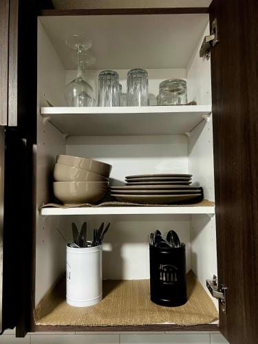 a cupboard with plates and utensils in it at Peaceful Homes - Elegant 2 Bedroom Suite in Calgary