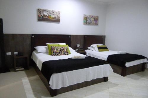 a bedroom with two beds with black and white sheets at Hotel La Casa N. 3 in Montería