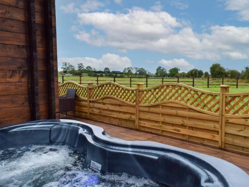 a hot tub on a deck with a fence at Pheasant Lodge - Uk33402 in Hungerton