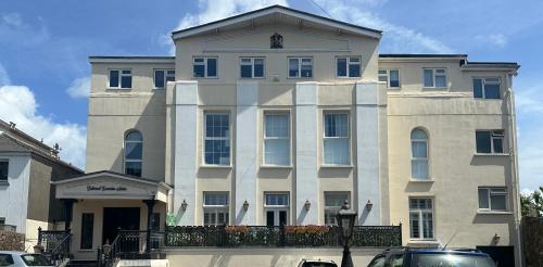 a large white building on a street with cars parked in front at Cute and Comfy Apartment in Saint Helier Jersey