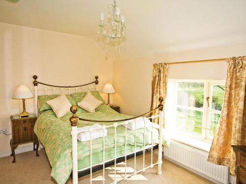 a bedroom with a bed with a chandelier and a window at Brook House Farm Cottage in Church Minshull