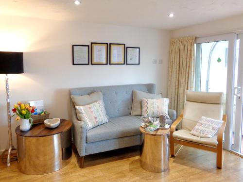 ein Wohnzimmer mit einem blauen Sofa und 2 Stühlen in der Unterkunft The Old Winery Cottage in Dymock