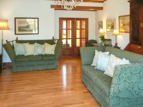 twee groene banken in een woonkamer met houten vloeren bij Dove Cote House in Westleigh