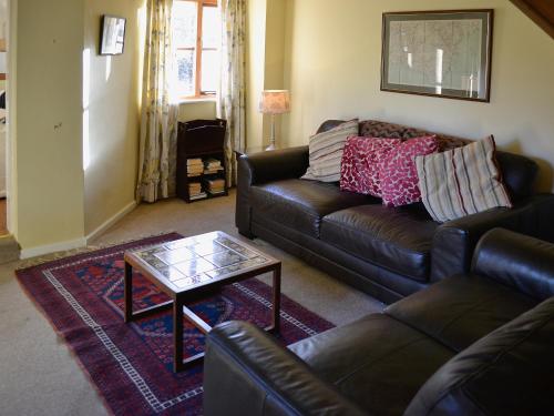 a living room with a leather couch and a coffee table at Bat's Cottage in Tipton Saint John
