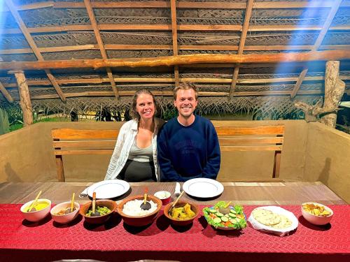 a man and woman sitting at a table with food at Udawalawe Safari House in Udawalawe