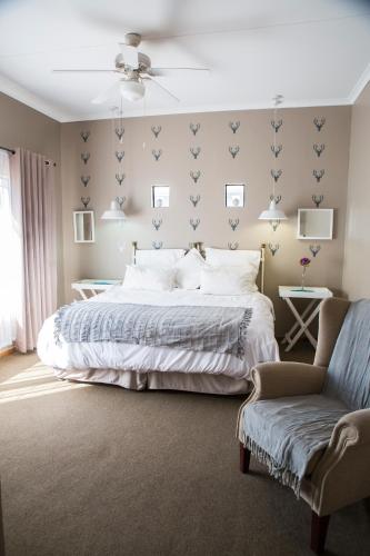 a bedroom with a large bed and a chair at Ons Dorpshuis Guesthouse in Rustenburg