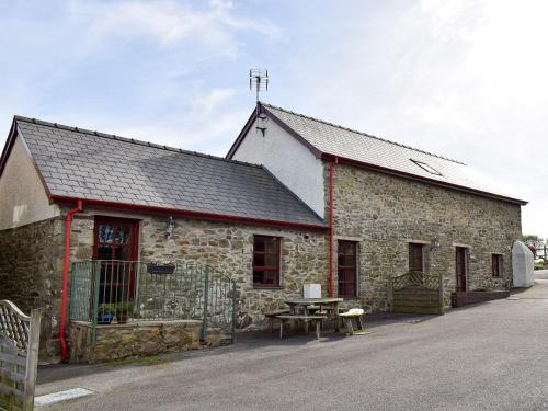 a stone building with a picnic table in front of it at The Granary- Osc in Penbryn