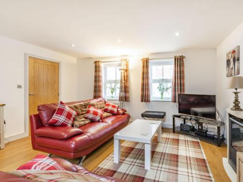 a living room with a leather couch and a table at Cobble Cottage - Uk38973 in Whitby