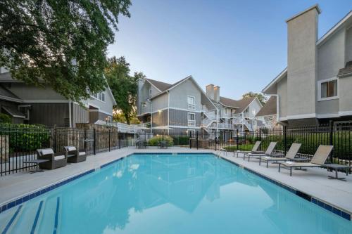 a swimming pool with lounge chairs next to a house at Residence Inn by Marriott Atlanta Cumberland/Galleria in Atlanta
