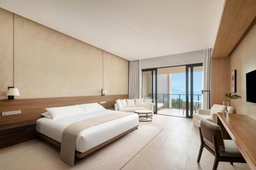 a bedroom with a large bed and a desk and chairs at The Sanya EDITION in Sanya
