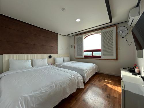 SongjŏngにあるGyeongpo Iris Stayのベッド2台と窓のある寝室