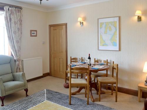 a living room with a dining room table and a chair at Anchorage in Maidens