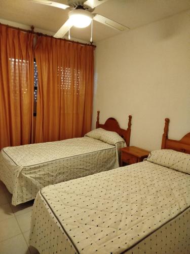 a bedroom with two beds and an orange curtain at TorrelagunaVera in Palomares