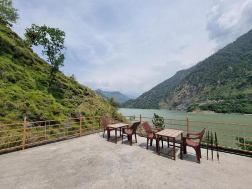 a group of tables and chairs next to a river at Chamera Inn Homestay in Chamba